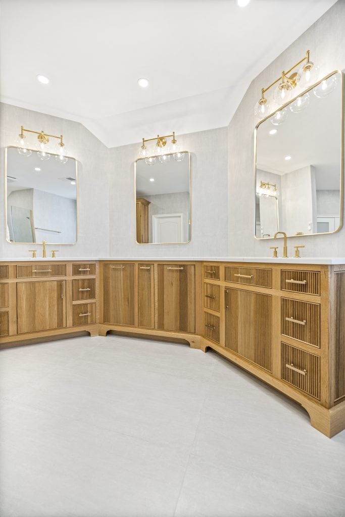 After: the vanity corner with three gold framed mirrors and sconces