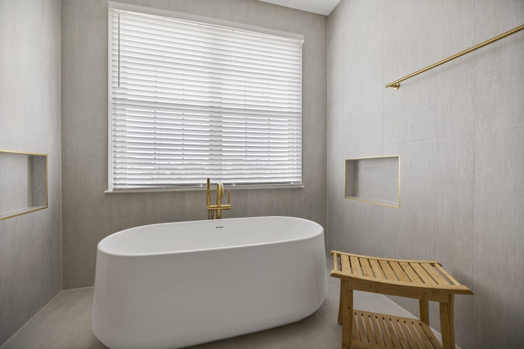 After: freestanding tub centred under the window with a recessed niche either side