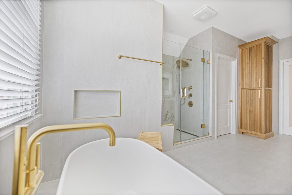 After: tub filler and recessed niche with the shower and tall oak linen cabinet beyond