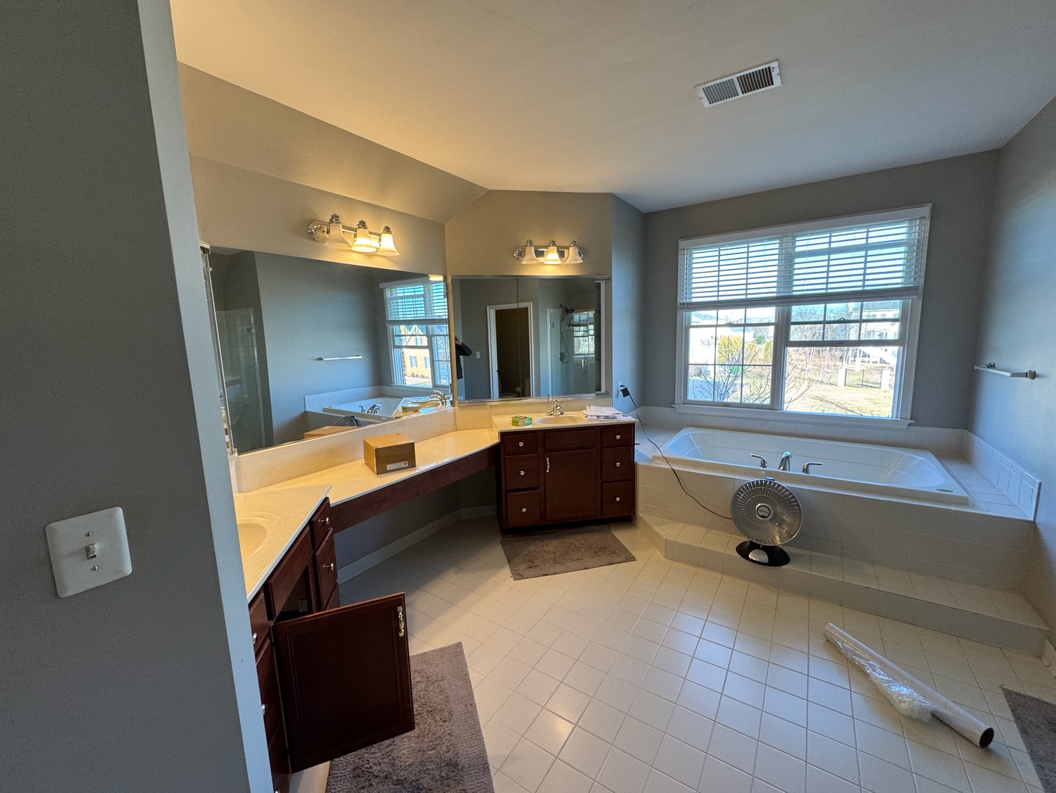 Spacious bathroom with double vanity, large mirrors, and wood cabinetry