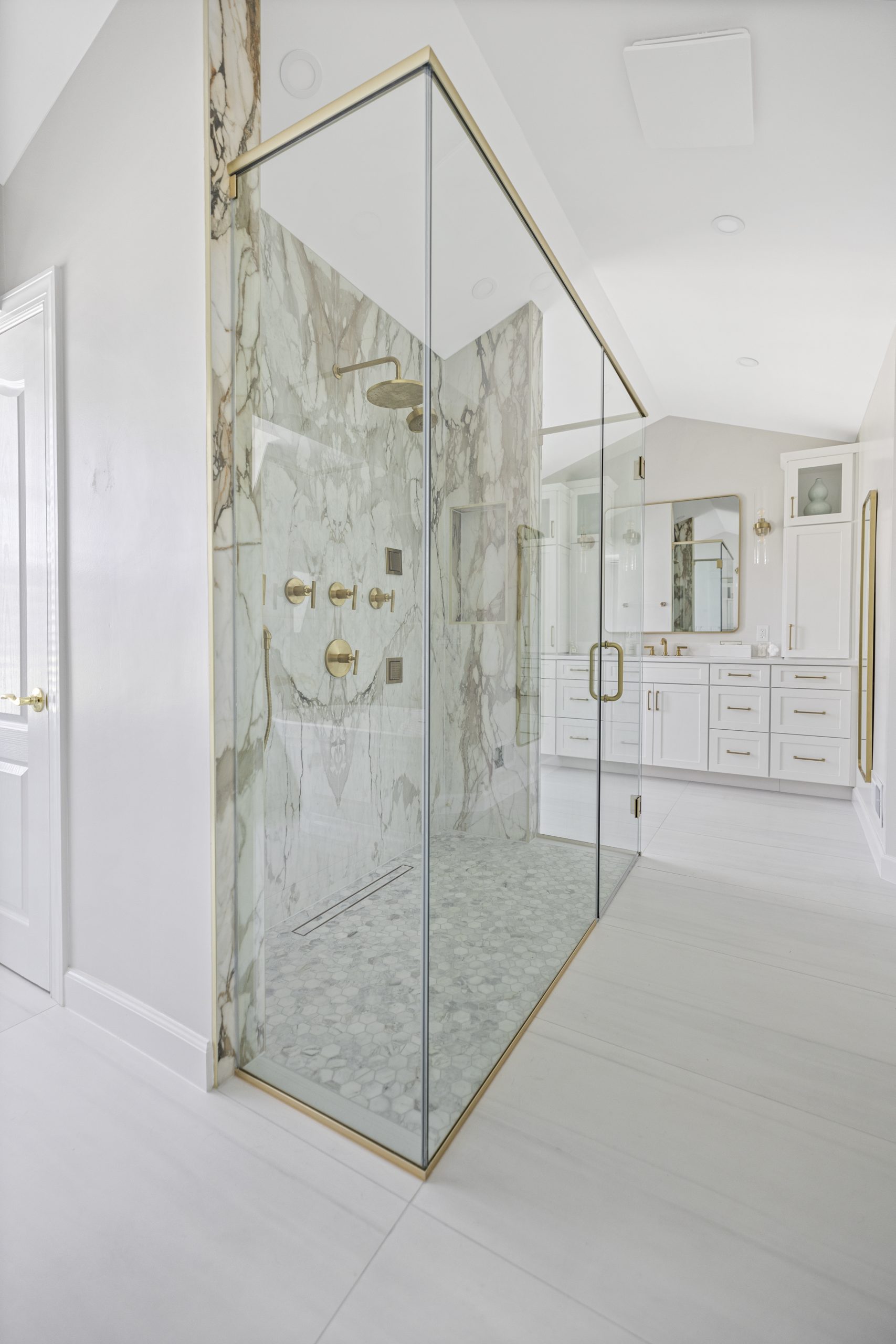 Luxurious walk-in shower with marble and gold fixtures in a Northern Virginia bathroom