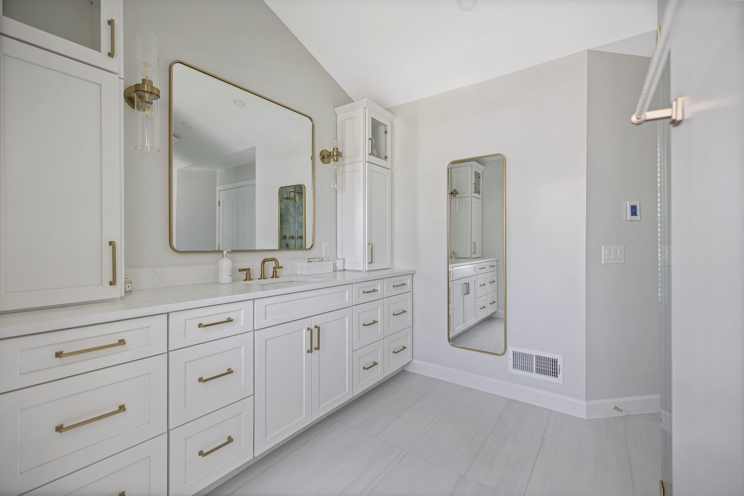 Modern spa bathroom with double vanity, large mirrors, and warm finishes