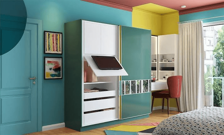 Modern bedroom with teal walls, wardrobe, vanity, chair, window curtains, and colorful decor accents.