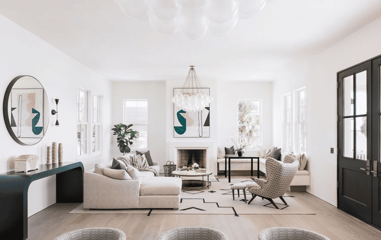 Bright living room with large windows, modern furniture, chandelier, and abstract art on the walls.