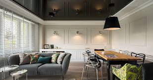 Modern living room featuring a gray sofa, colorful pillows, dining table, chairs, and large windows.