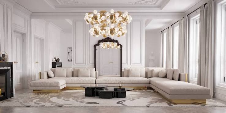 Elegant living room with a large beige sectional sofa, modern chandelier, and tall windows on both sides.