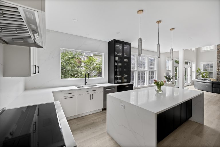 Modern kitchen with white cabinets, a spacious island, pendant lights, and big windows with natural light.