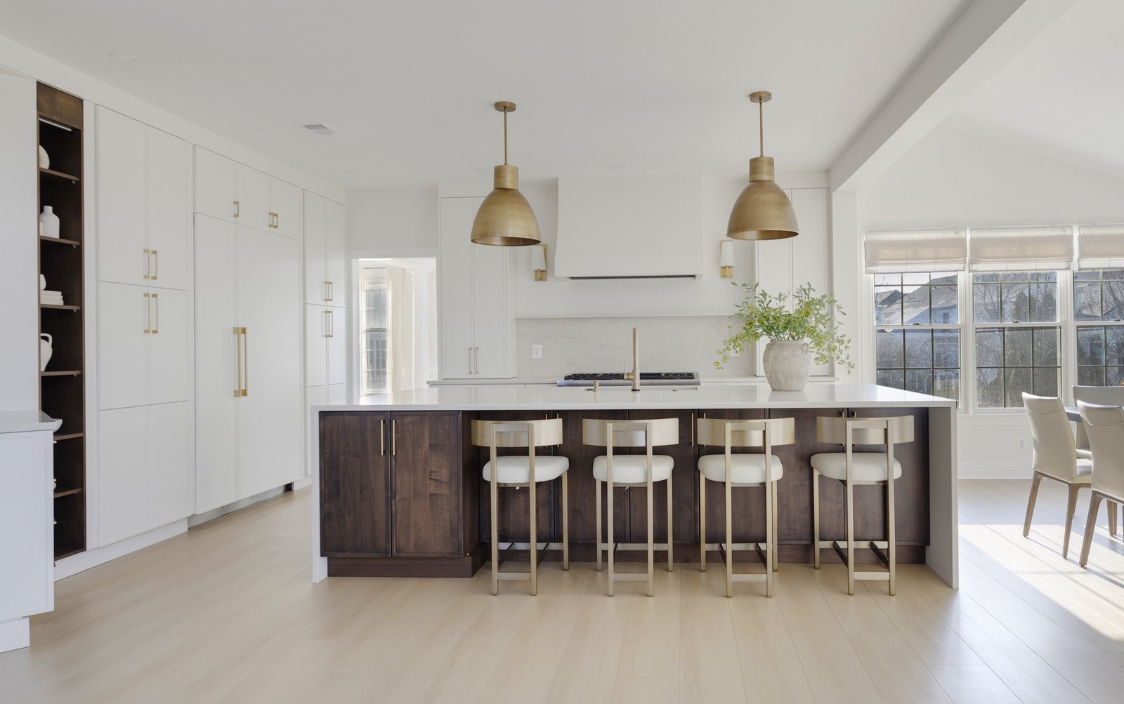 White kitchen with a dark walnut island, brass pendants and four gold stools in a remodeled Chantilly, VA home