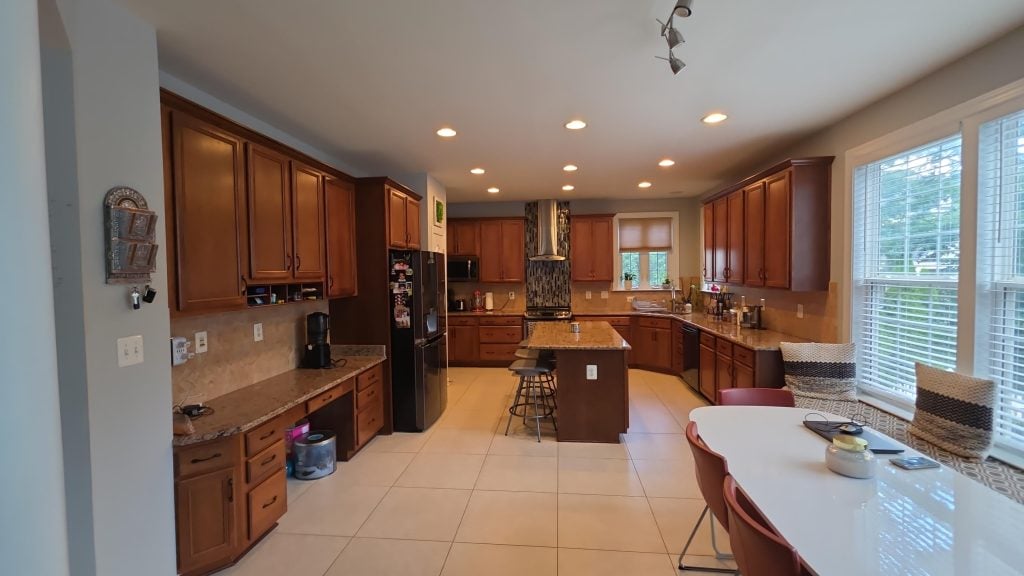 Spacious kitchen featuring wooden cabinets, a center island, modern appliances, and a white dining table.