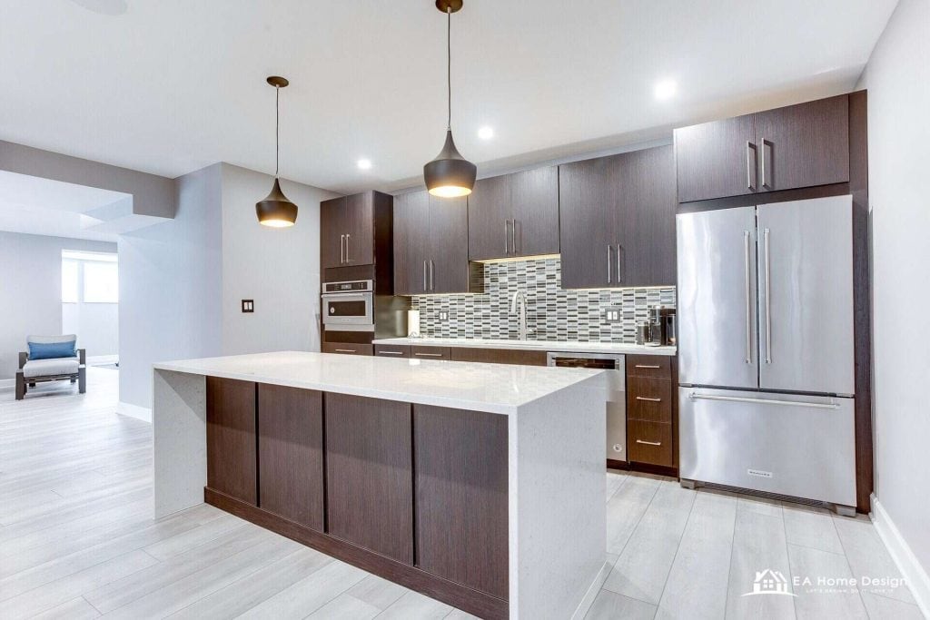 Finished basement kitchenette by EA Home Design in Northern Virginia: dark flat-panel cabinets, a quartz waterfall island, pendant lights and stainless appliances
